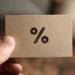 Una mano tiene un cartoncino marrone con il simbolo del segno percentuale (%) ritagliato.