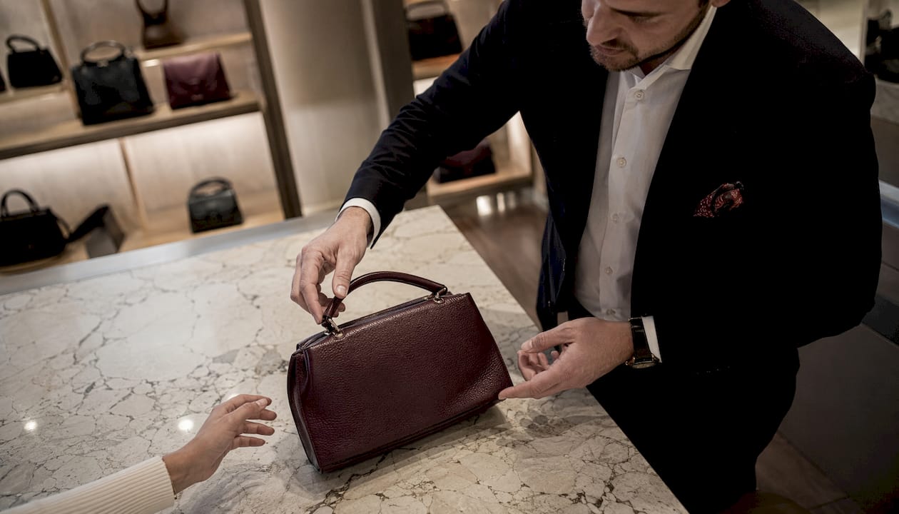 Luxury Platform Exclusivity Tactics List for 2026 Hands arranging luxury handbag in boutique